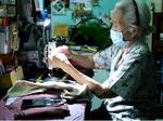 Elderly woman sews clothes to help the needy